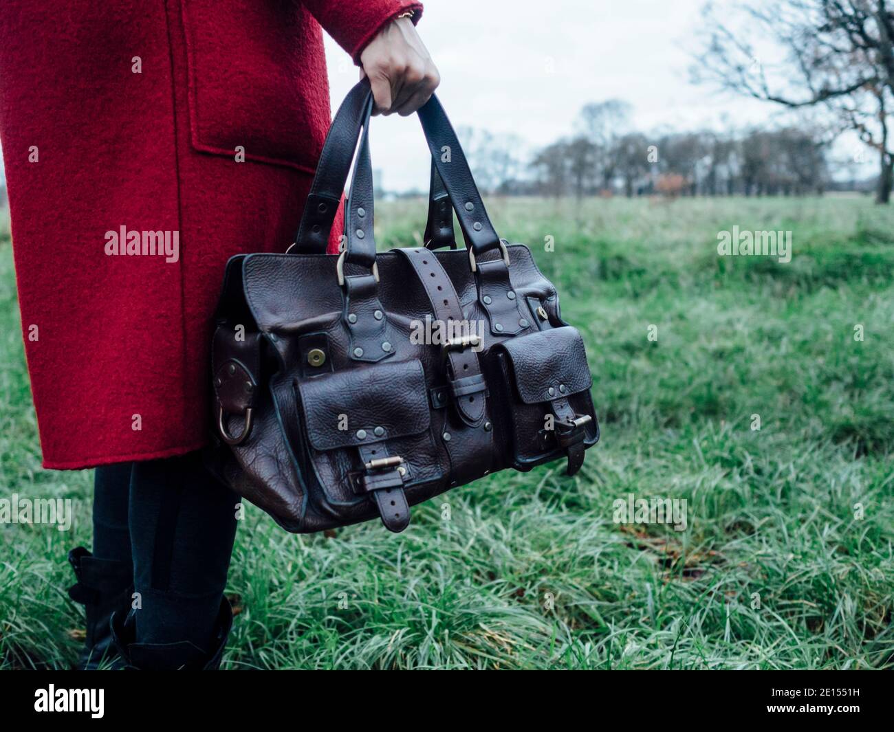 Donna in soprabito rosso con una borsa in pelle di design Foto Stock