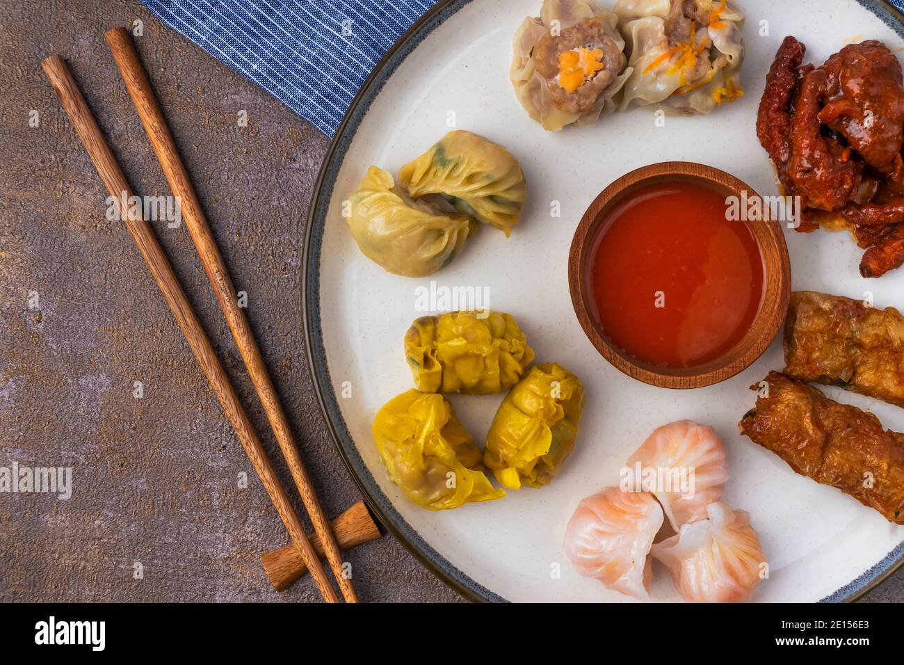 varie varianti di dim sum in piastre in ceramica e legno bastoncini di pollo Foto Stock