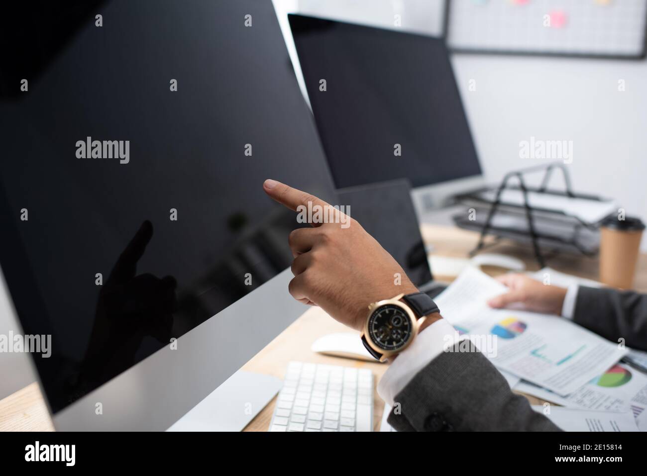 vista ritagliata del commerciante in orologio da polso puntando al monitor con schermata vuota Foto Stock
