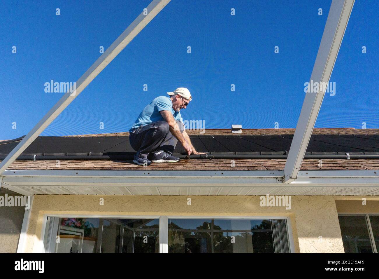 uomo di 60 anni sul tetto ispezionando riscaldatore solare in Florida Foto Stock