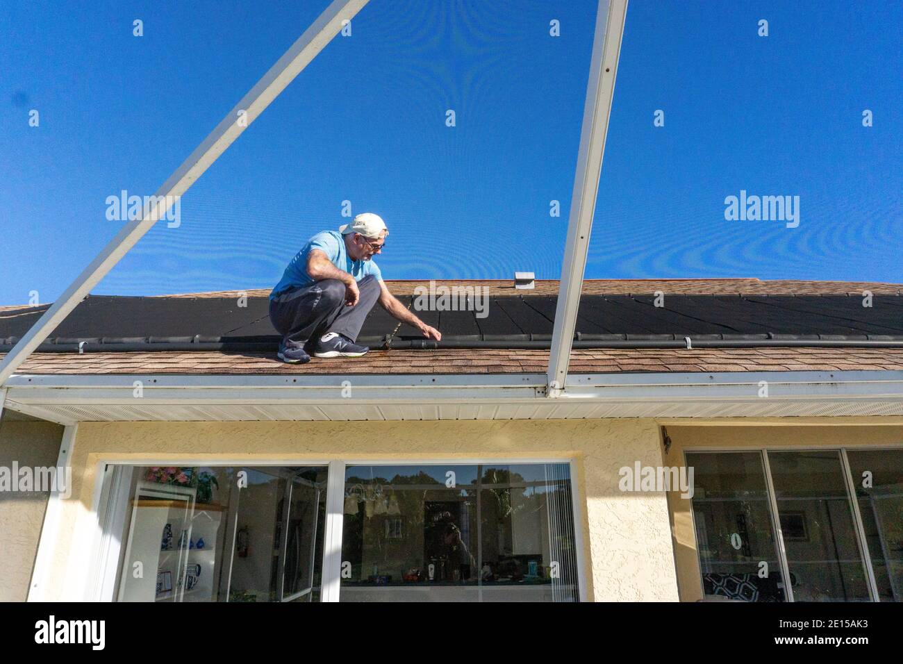 Vecchio uomo sul tetto ispezionando l'impianto di riscaldamento dell'acqua solare in Florida Foto Stock