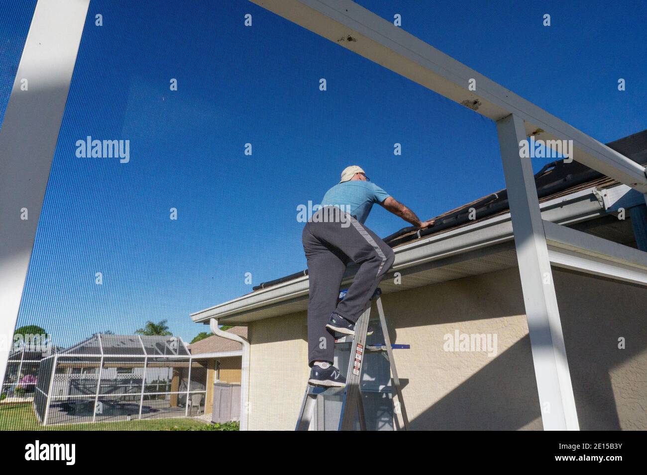 l'uomo di 60 anni sale a scala per salire su Tetto della casa della Florida Foto Stock