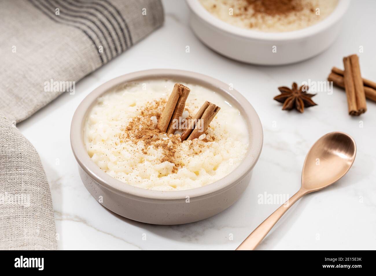Budino di riso cremoso con cannella in ciotola su tavolo di marmo bianco. Tipico dessert spagnolo Foto Stock