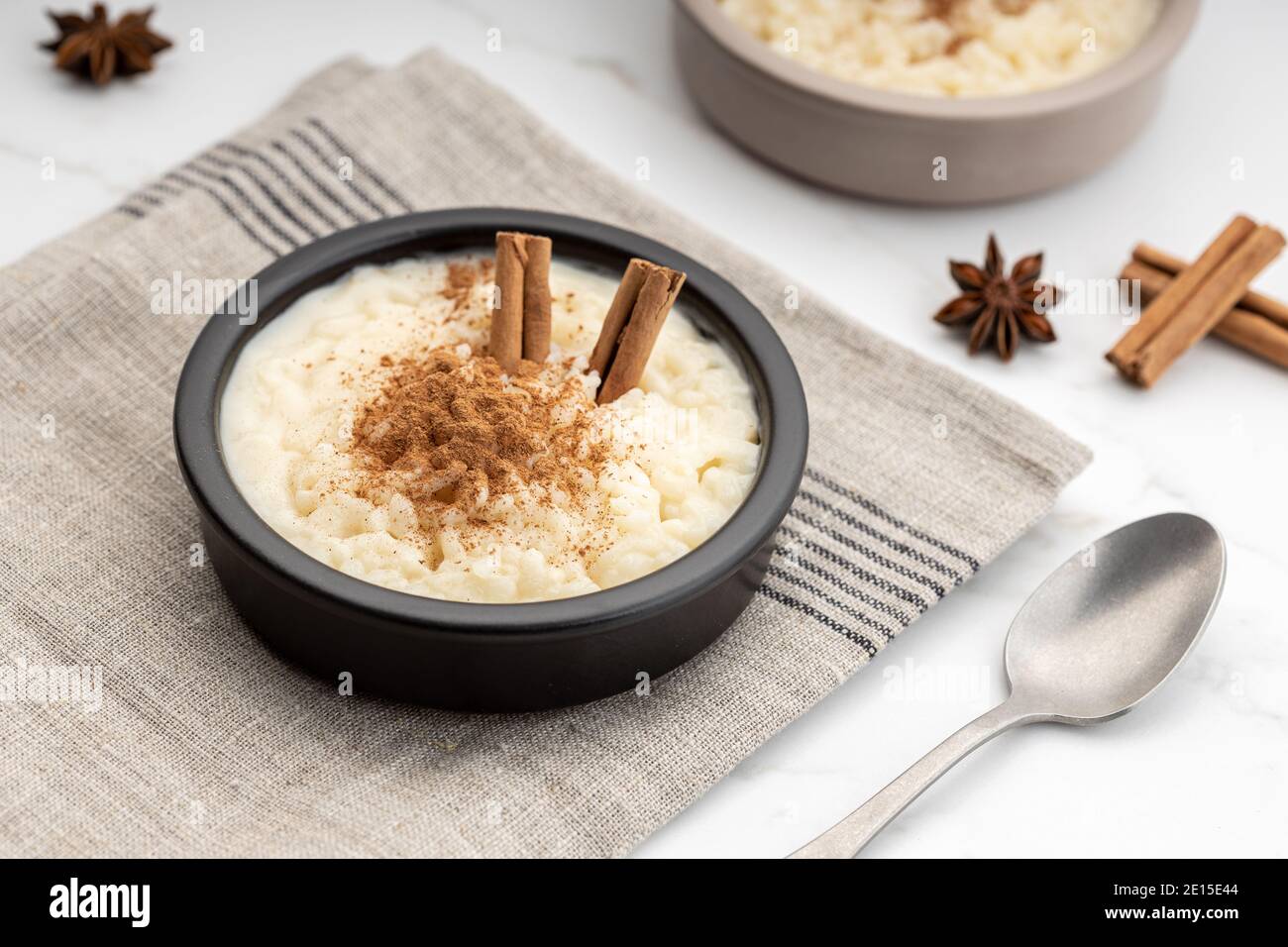 Budino di riso cremoso con cannella in ciotola su tavolo di marmo bianco. Tipico dessert spagnolo Foto Stock