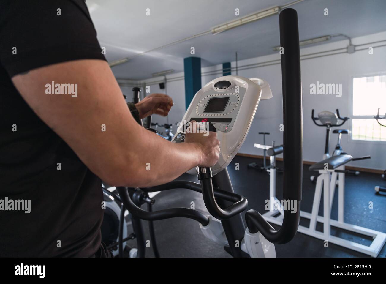 Uomo irriconoscibile mani su corrimano ellittico dell'addestratore nel randello di sport. Cardio allenamento sfondo, in esecuzione su tapis roulant. Stile di vita sano, ragazzo traini Foto Stock