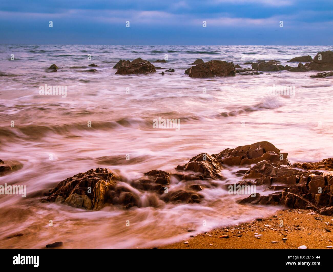 Spiaggia costa con Motion acque sfocate e rocce Foto Stock