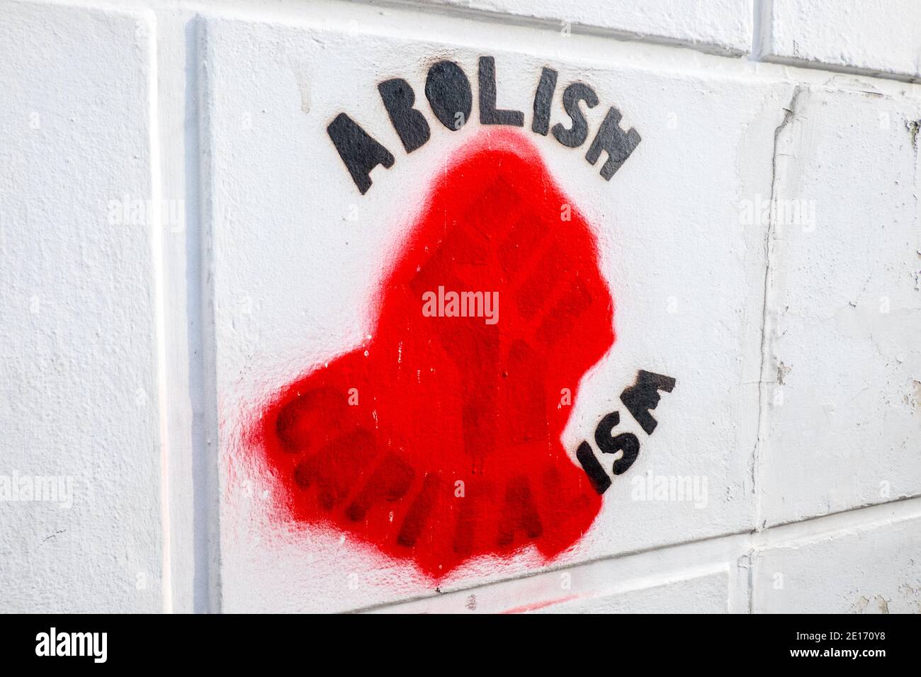 Abolire capitalism graffiti,graffiti,murale,on,wall,has,been changed, vandalized,to,abolire ism, ism,.Looks like a John Lennon,lyric,from Give Peace a Chance...Everybody's Talking About Bagism, Shagism, Dragism, Madism Ragism, Tagism, This-ism, ISM, ism, ism, ism, ism, ism, ism. Pugno clenched, oscurato,rimosso,sinistra,ala,politica. Su muro nel centro di Aberystwyth, Cardigan Bay, Ceredigion.Student, città sulla costa, costa, impostazione, Galles occidentale, Galles, Galles, Regno Unito,. Foto Stock