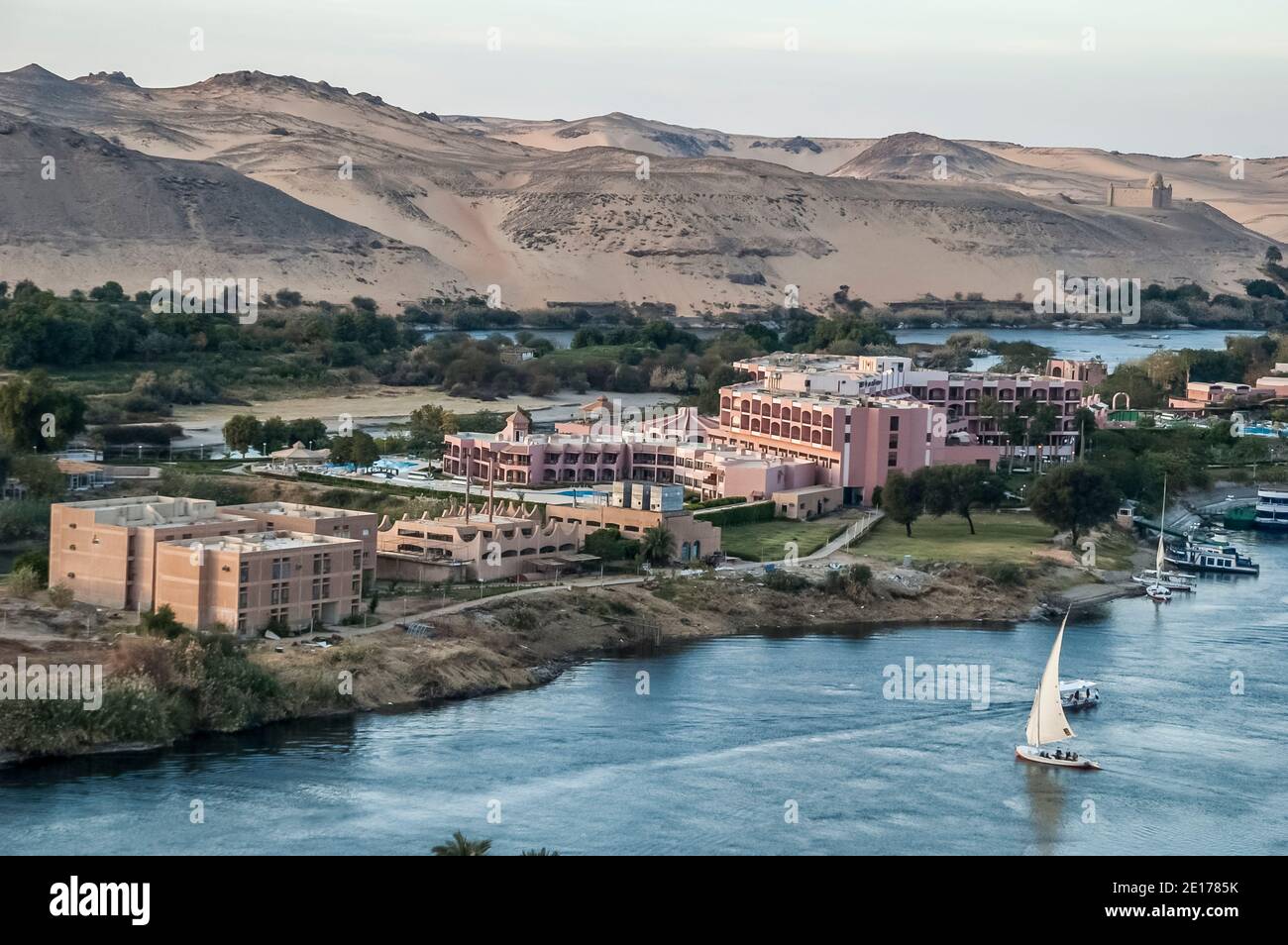 Questa tranquilla scena con le barche a vela Felucca sul fiume Nilo si trova presso l'antica città egiziana di Assuan, precedentemente conosciuta come la città nubiana, guardando a sud verso il luogo di sepoltura delle Tombe dei Nobili e del Mausoleo dell'Aga Khan. La zona è importante in quanto era un posto di sosta per l'esercito britannico che passa attraverso l'Egitto al Sudan da dove Lord Kitchener ristabilì la pace nella regione. Per questo fu dotato della terra conosciuta come Isola di Kitchener che Lord Kitchener trasformò in uno dei primi giardini botanici del mondo Foto Stock