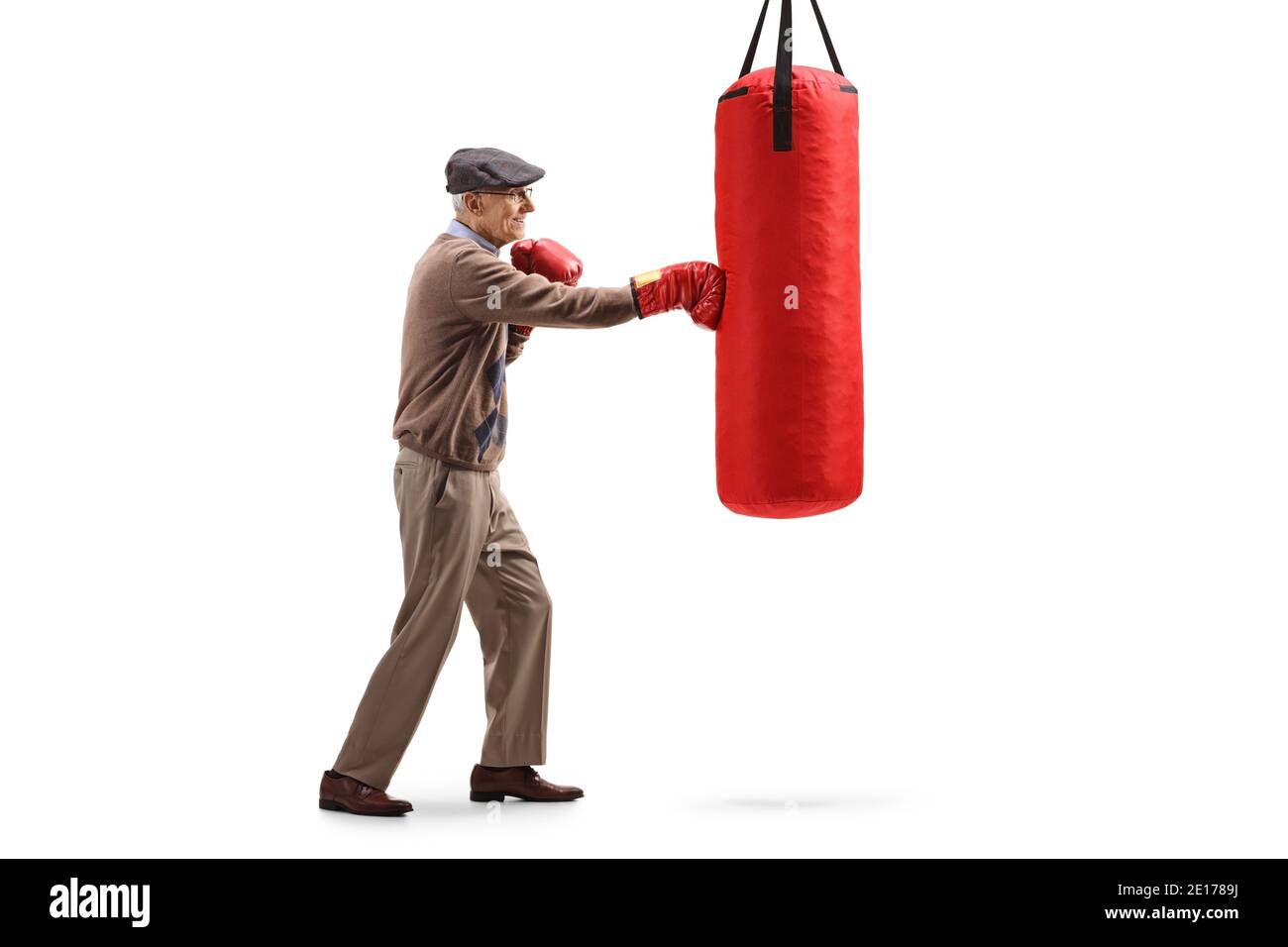 Scatto di profilo di lunghezza intera di un uomo anziano che punzona borsa con guanti rossi da boxe isolati su sfondo bianco Foto Stock