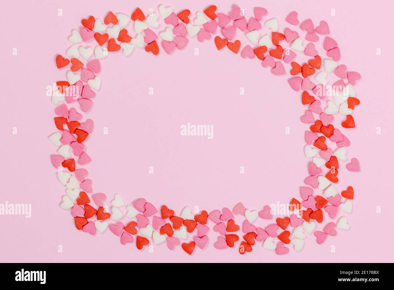 Caramelle a forma di cuore sparse su fondo rosa amore concetto di matrimonio. Sfondo del modello di giorno di San Valentino. Vista dall'alto in posizione piatta. Spazio di copia Foto Stock