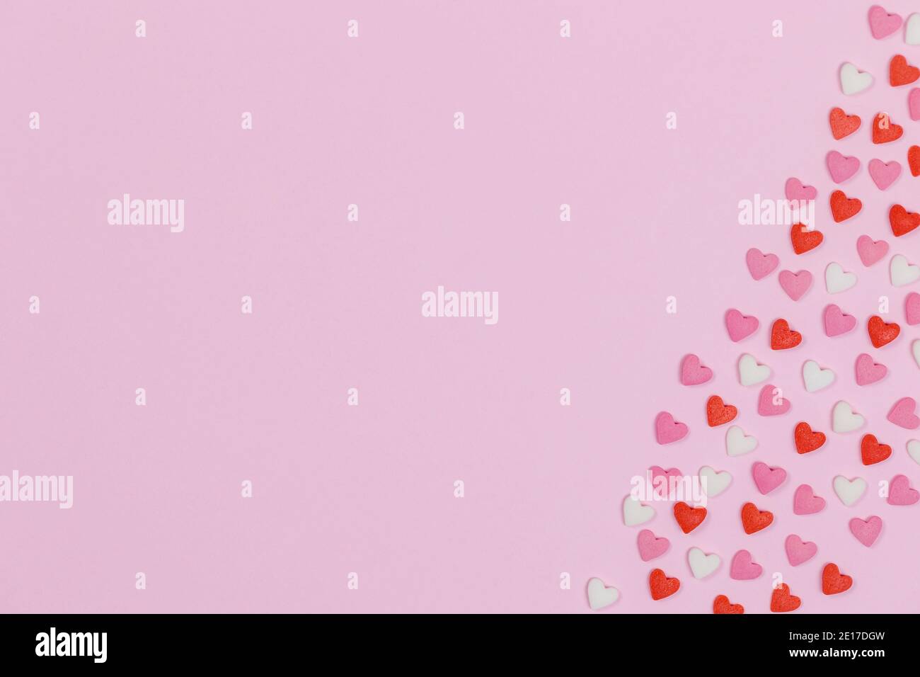 Caramelle a forma di cuore sparse su fondo rosa amore concetto di matrimonio. Sfondo del modello di giorno di San Valentino. Vista dall'alto in posizione piatta. Spazio di copia Foto Stock