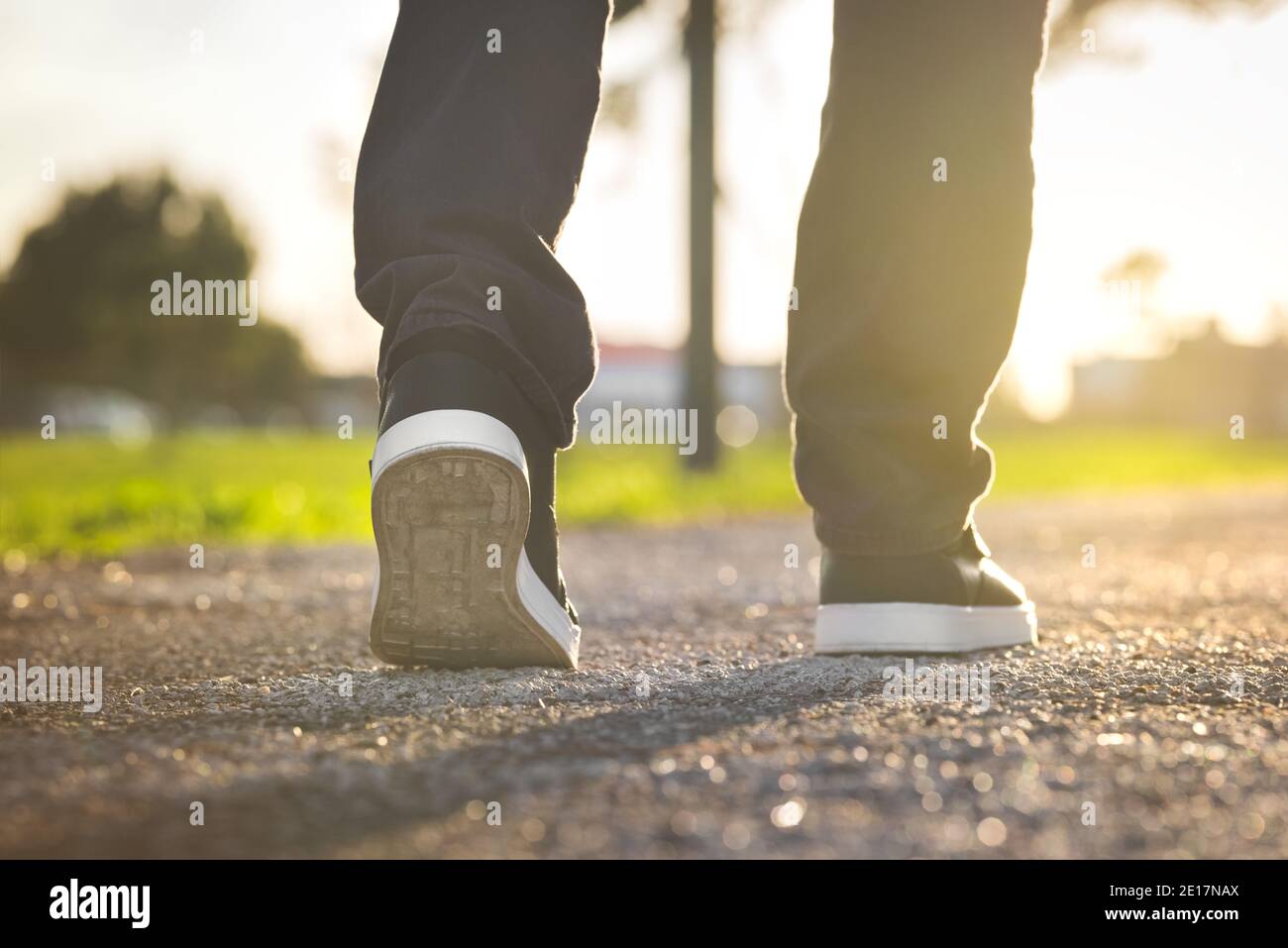Uomo che cammina all'aperto nel parco al tramonto. Primo piano sulla scarpa Foto Stock