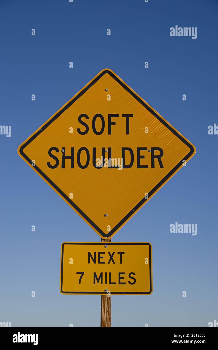 soft shoulder next 7 miles road segno con cielo blu sfondo Foto Stock
