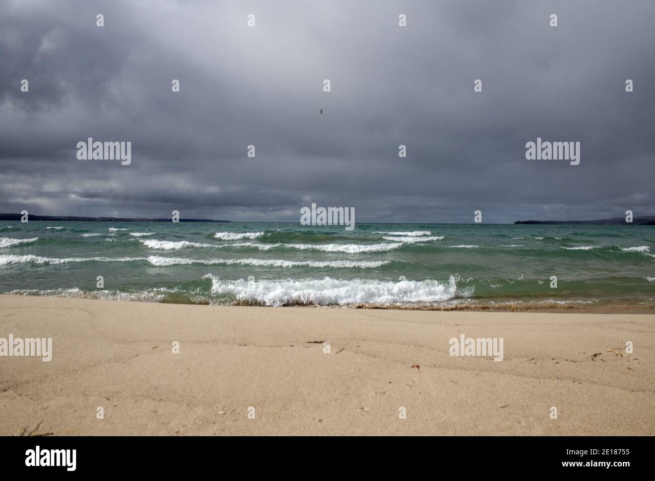 Tempesta sull'orizzonte. Le onde si infrangono su una spiaggia del lago Michigan nel Petoskey state Park, con le nuvole buie minacciose all'orizzonte. Foto Stock