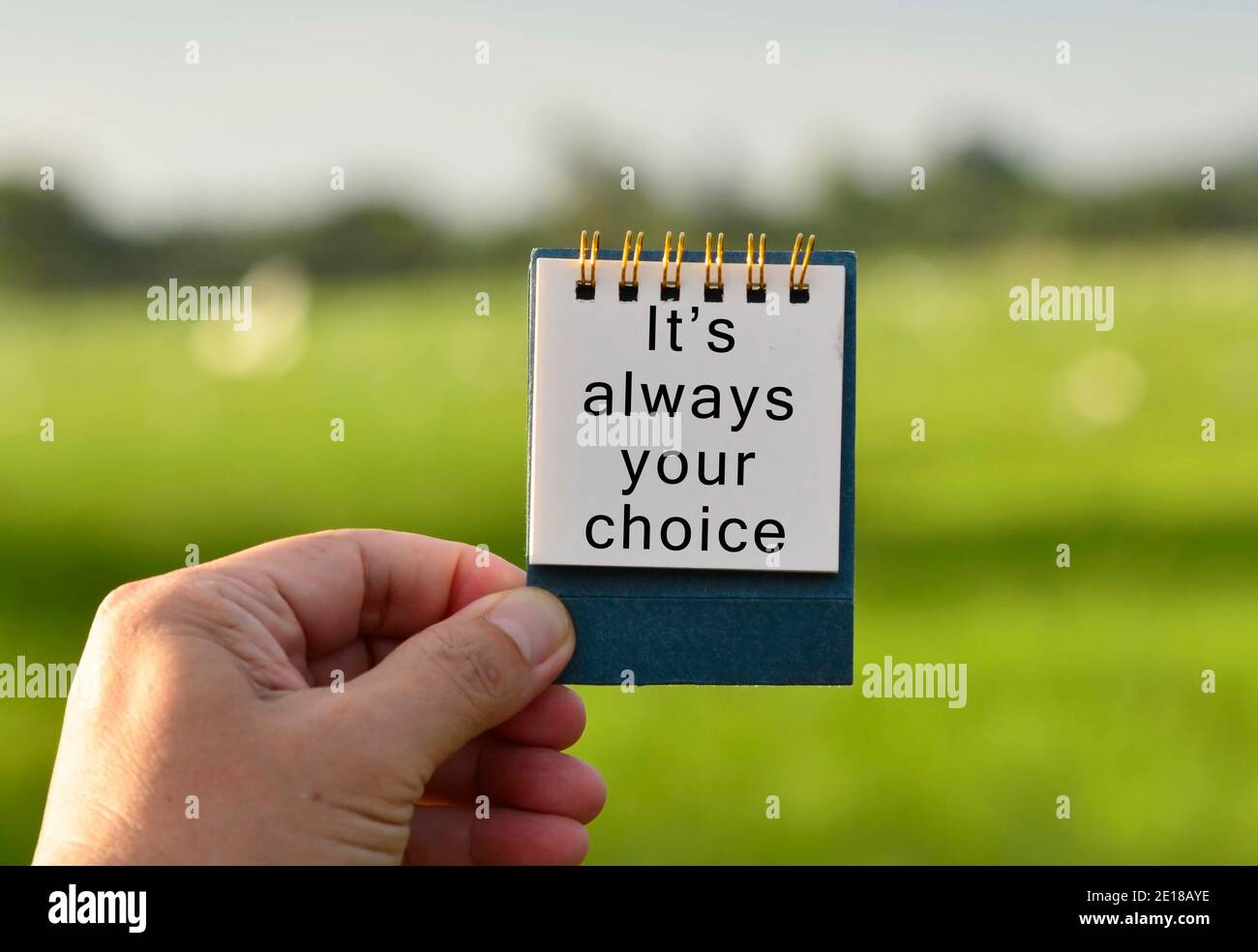 Mani che tiene UN blocco note bianco con testo scritto e sfocato Sfondo verde Foto Stock