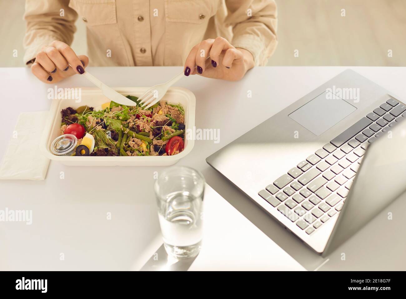 Studente occupato con sano pranzo da asporto dal contenitore durante il pasto giorno lavorativo Foto Stock