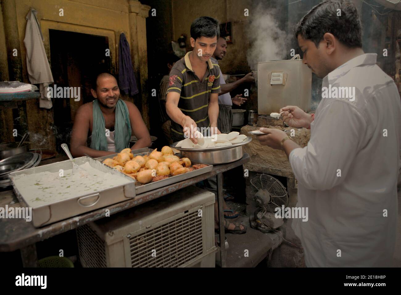 Lavoratori che prestano servizio a un cliente presso un fornitore di prodotti alimentari a Varanasi, Uttar Pradesh, India. Foto Stock