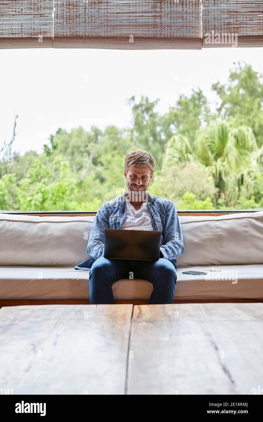 Uomo medio sorridente che usa il computer portatile Foto Stock