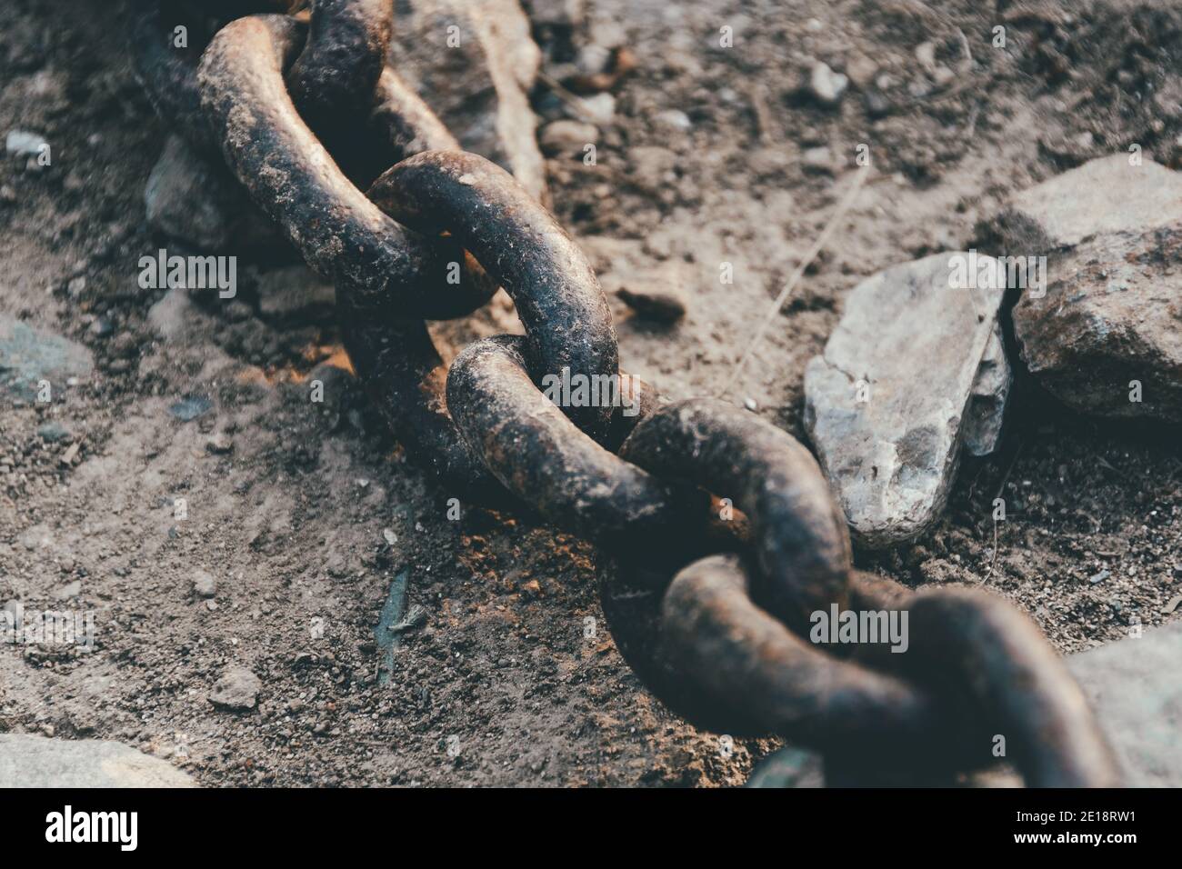 Vecchia catena di ferro con anelli arrugginiti su pietre Foto Stock