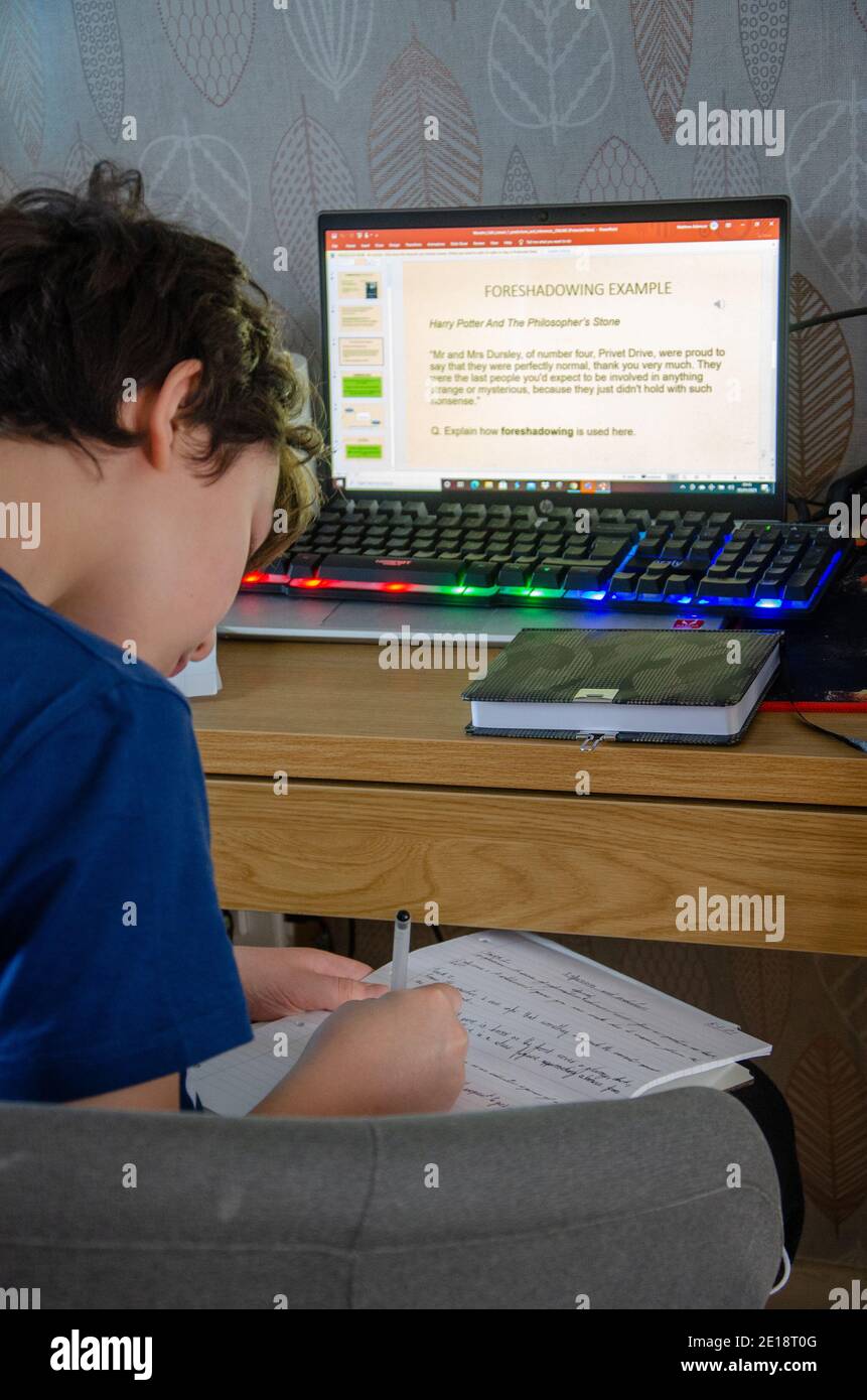 Reading, UK - 5 gennaio 2021: A seguito dell'annuncio del primo ministro britannico Boris Johnson che l'Inghilterra deve entrare in un nuovo blocco a causa del coronavirus, un bambino della scuola secondaria si siede a casa davanti al computer portatile di famiglia per fare l'apprendimento online. La sua scuola ha inviato lezioni sotto forma di presentazioni di Microsoft PowerPoint e comunica con i bambini tramite strumenti come i team Microsoft. Foto Stock