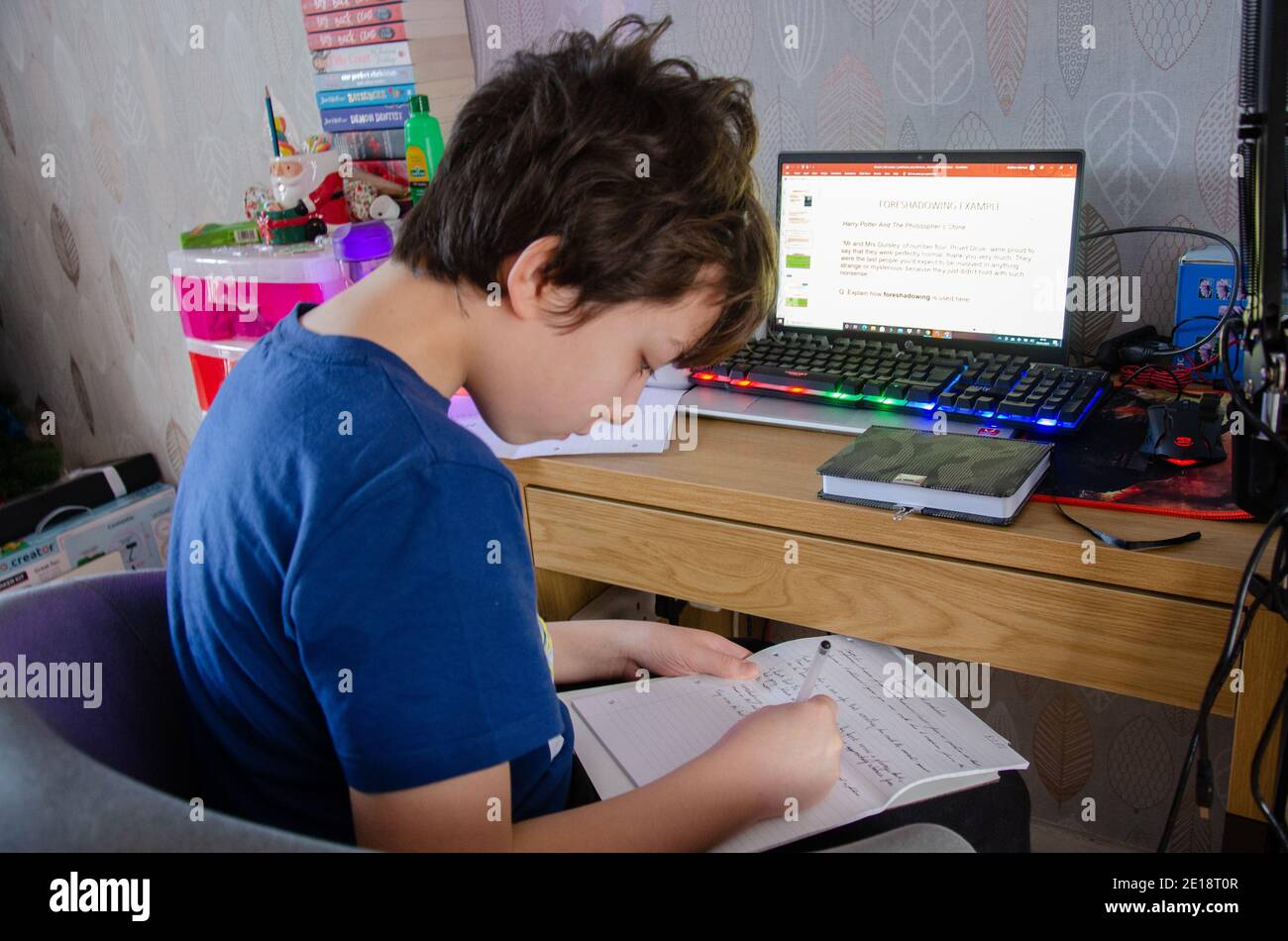 Reading, UK - 5 gennaio 2021: A seguito dell'annuncio del primo ministro britannico Boris Johnson che l'Inghilterra deve entrare in un nuovo blocco a causa del coronavirus, un bambino della scuola secondaria si siede a casa davanti al computer portatile di famiglia per fare l'apprendimento online. La sua scuola ha inviato lezioni sotto forma di presentazioni di Microsoft PowerPoint e comunica con i bambini tramite strumenti come i team Microsoft. Foto Stock