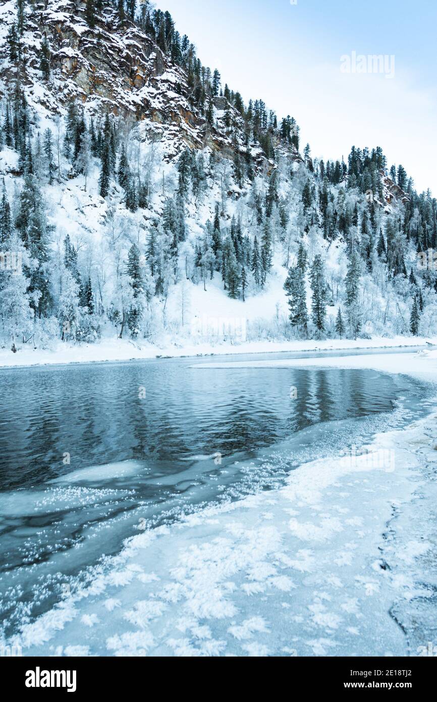 Riva ghiacciata del lago con foresta innevata. Clima freddo, letto del fiume ghiacciato a causa di un brusco scatto freddo Foto Stock