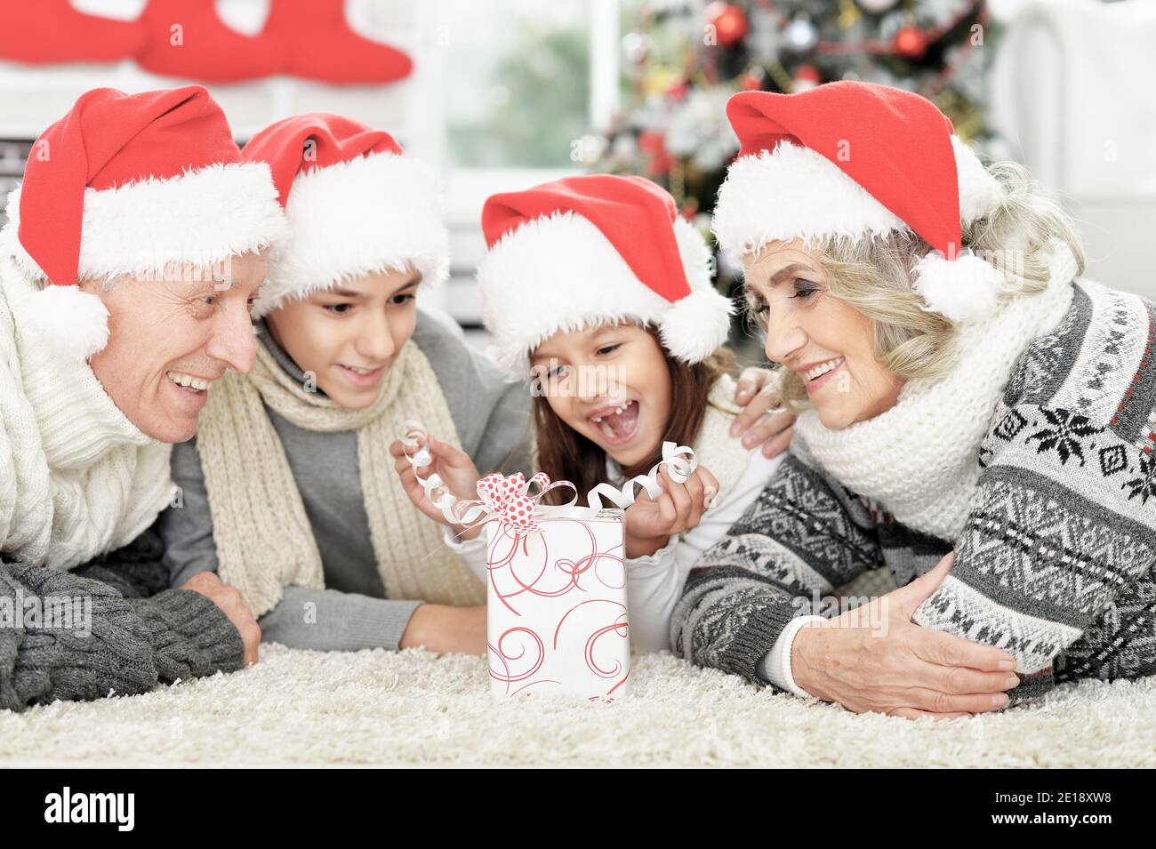 Felice famiglia a Santa cappelli sul pavimento con regalo Foto Stock