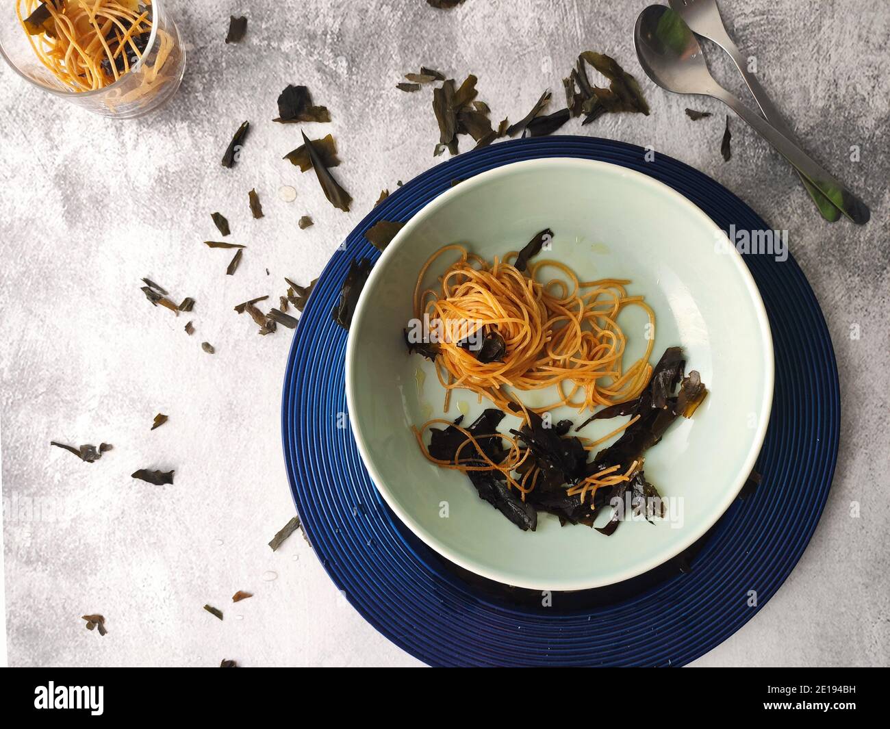 Gli spaghetti alle alghe kombu in un piatto blu Foto Stock