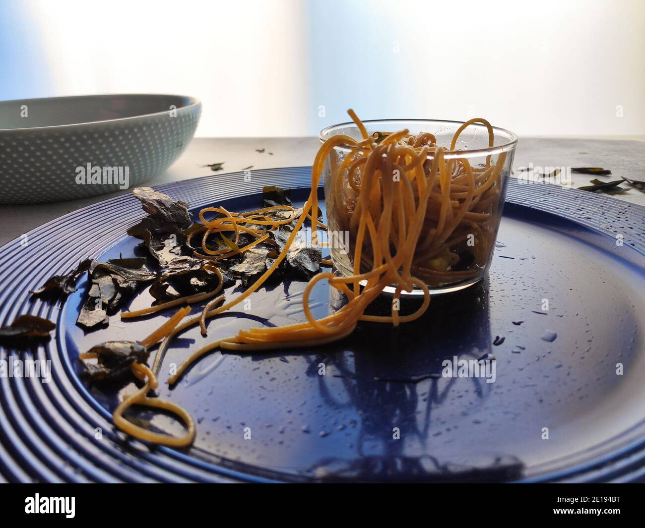 Gli spaghetti alle alghe kombu in un piatto blu Foto Stock