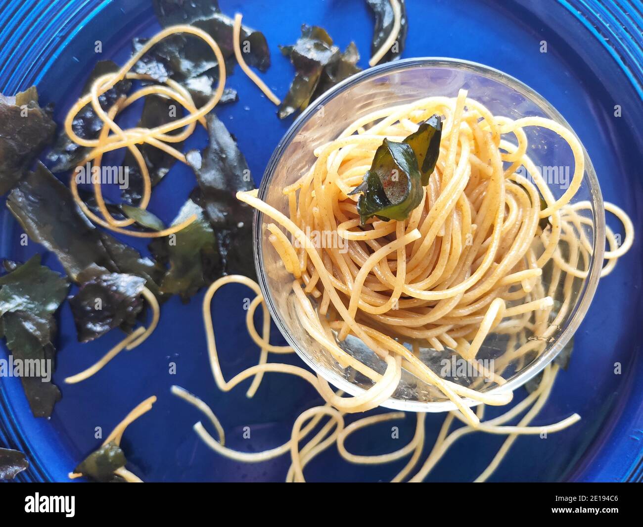 Gli spaghetti alle alghe kombu in un piatto blu Foto Stock