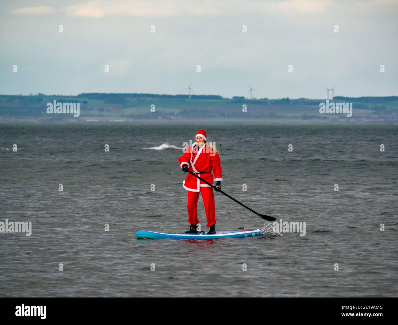 Evento benefico della comunità: Paddle boarder in costume di Santa, Firth of Forth, East Lothian, Scozia, Regno Unito Foto Stock