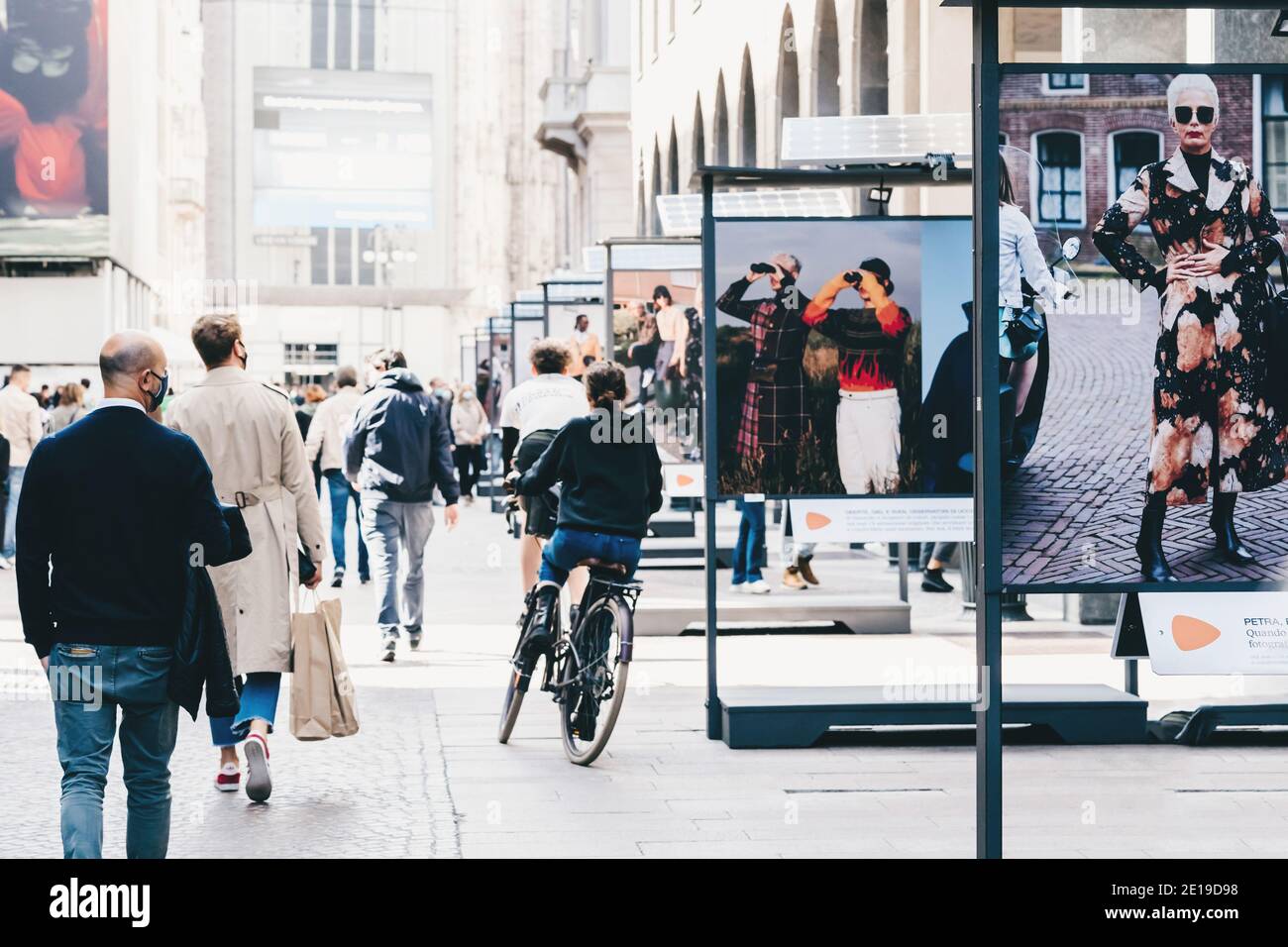 Persone in maschere strada a piedi nel centro di Milano, pendolari, in bicicletta. Mostra di strada di fotografia di moda moderna con l'uso di batterie solari Foto Stock