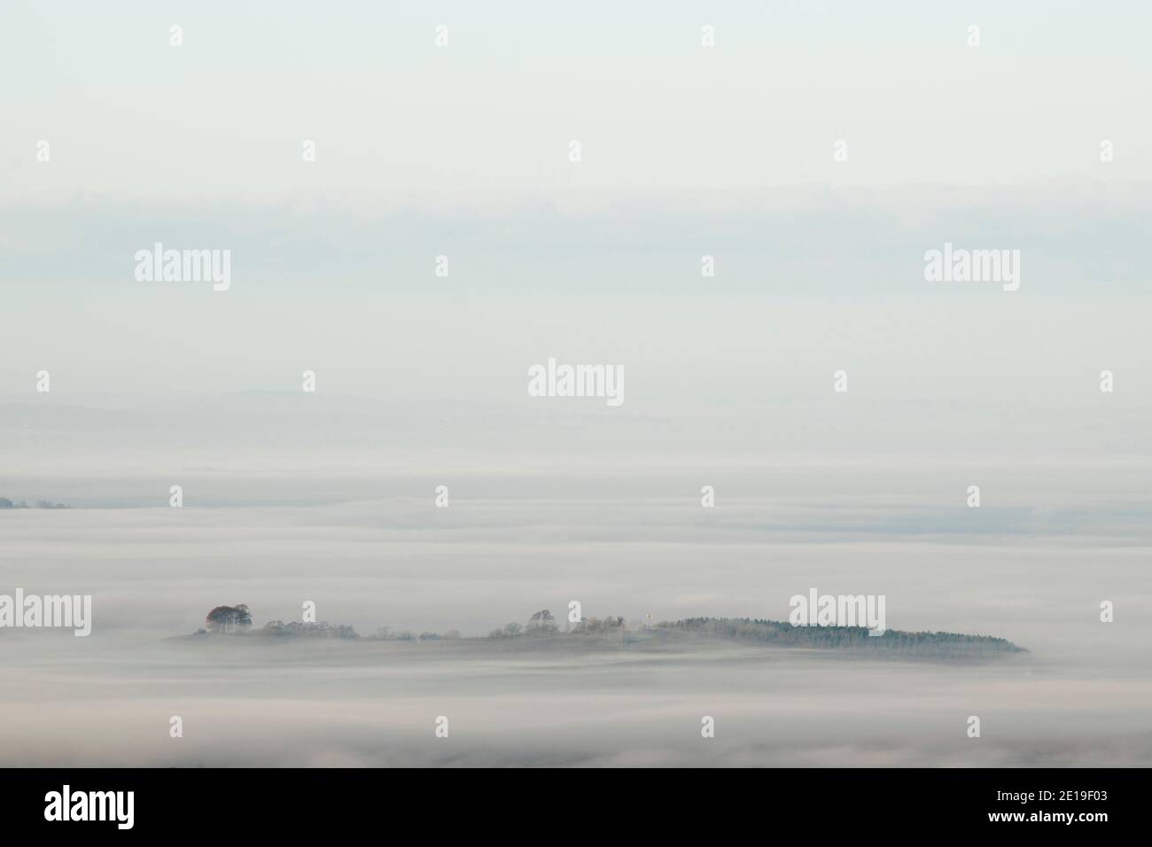 Strati di nebbia in una valle in campagna con colline, campi verdi e terreni agricoli con una splendida vista del paesaggio tipico inglese, scenario rurale sopra le nuvole nel Cotswolds, Inghilterra, Regno Unito Foto Stock