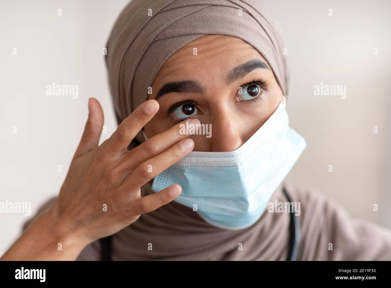 Sopraffarito medico femminile in hijab che tocca i suoi occhi Foto Stock