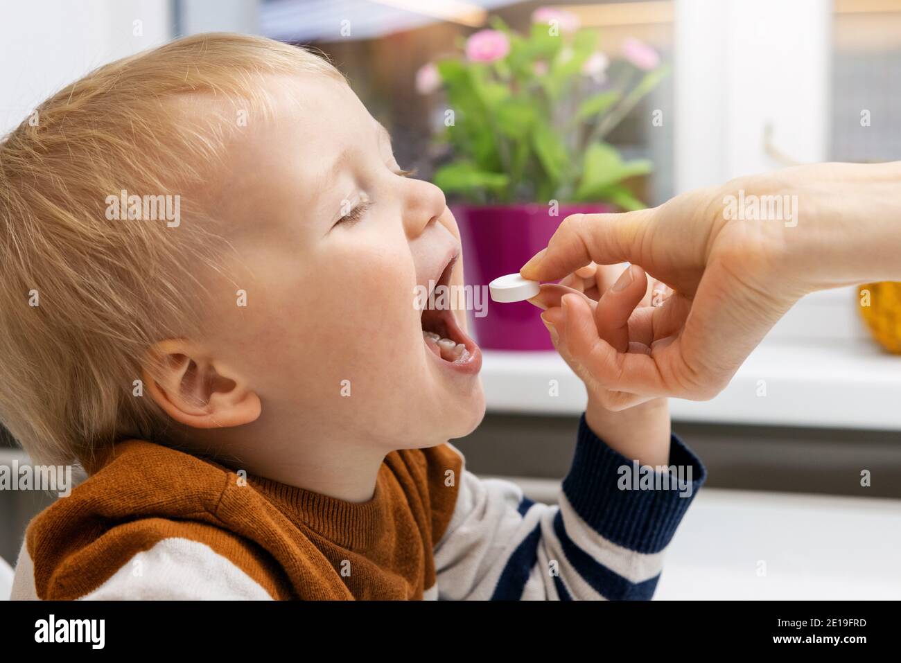 madre che dà la pillola della vitamina c al suo bambino. supplementi dietetici per i capretti Foto Stock