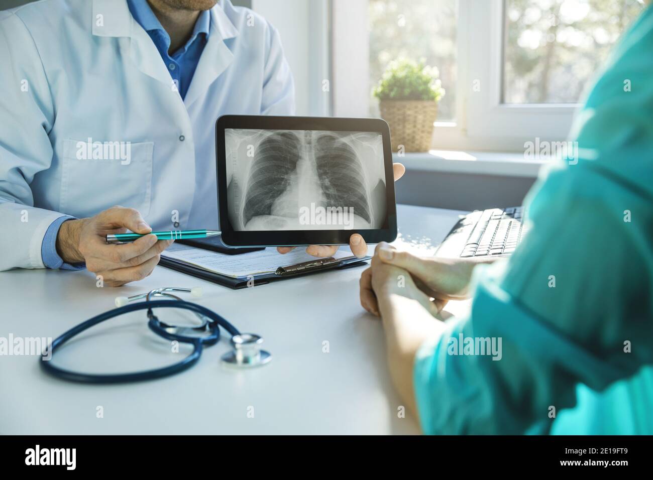 il medico e il paziente discutono i risultati della radiografia toracica su tablet digitale in ambulatori Foto Stock