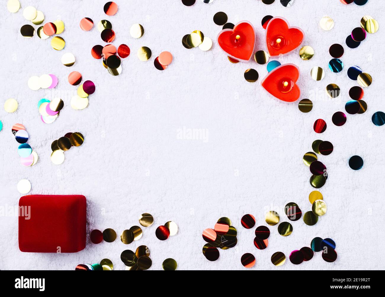Confetti colorati, candele a forma di cuore e ring box. Spazio per la pubblicità. Giorno di San Valentino e concetto di proposta. Foto Stock