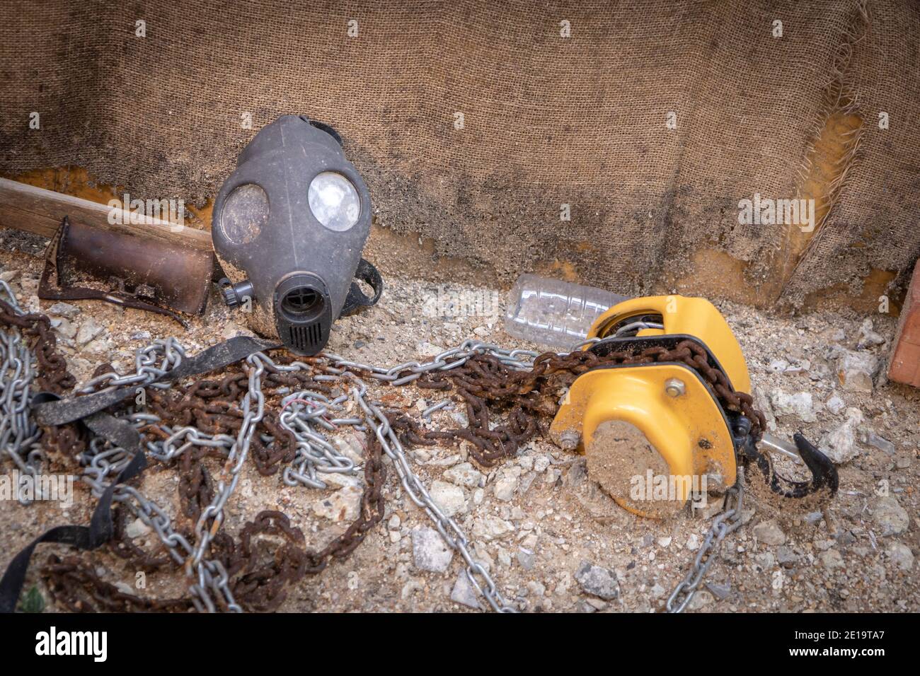 Vecchia maschera a gas all'interno delle rovine industriali abbandonate, tra catene arrugginite in metallo Foto Stock