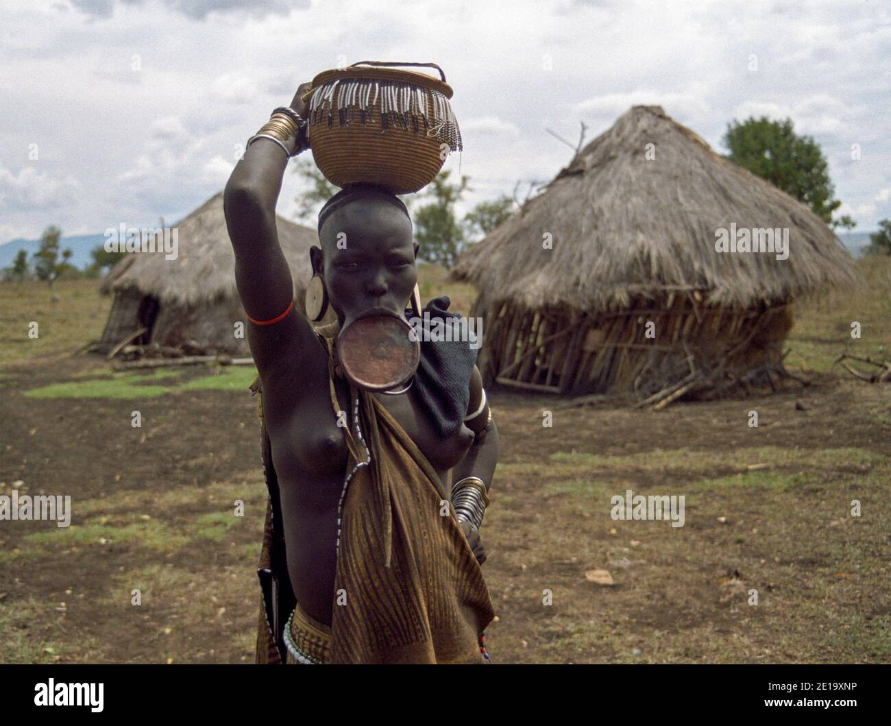 Donna tribù Mursi con piatto e cesto in testa, Omo Valley, Etiopia sudoccidentale Foto Stock