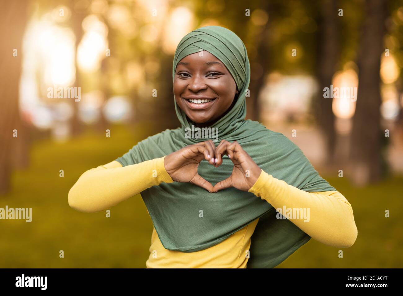 Concetto di amore. Donna musulmana africana sorridente in Hijab mostrando cuore Gesture Foto Stock