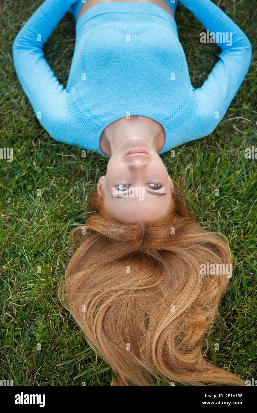 Vista dall'alto verticale di una bella donna sorridente, adagiata su un'erba verde Foto Stock