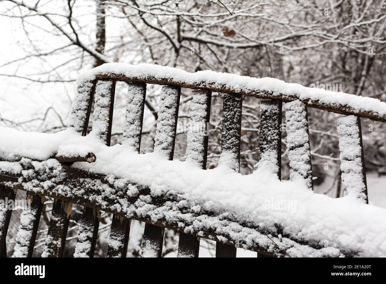 Recinzione in legno rotta coperta da neve fresca da vicino. Inverno nevicata al villaggio Foto Stock