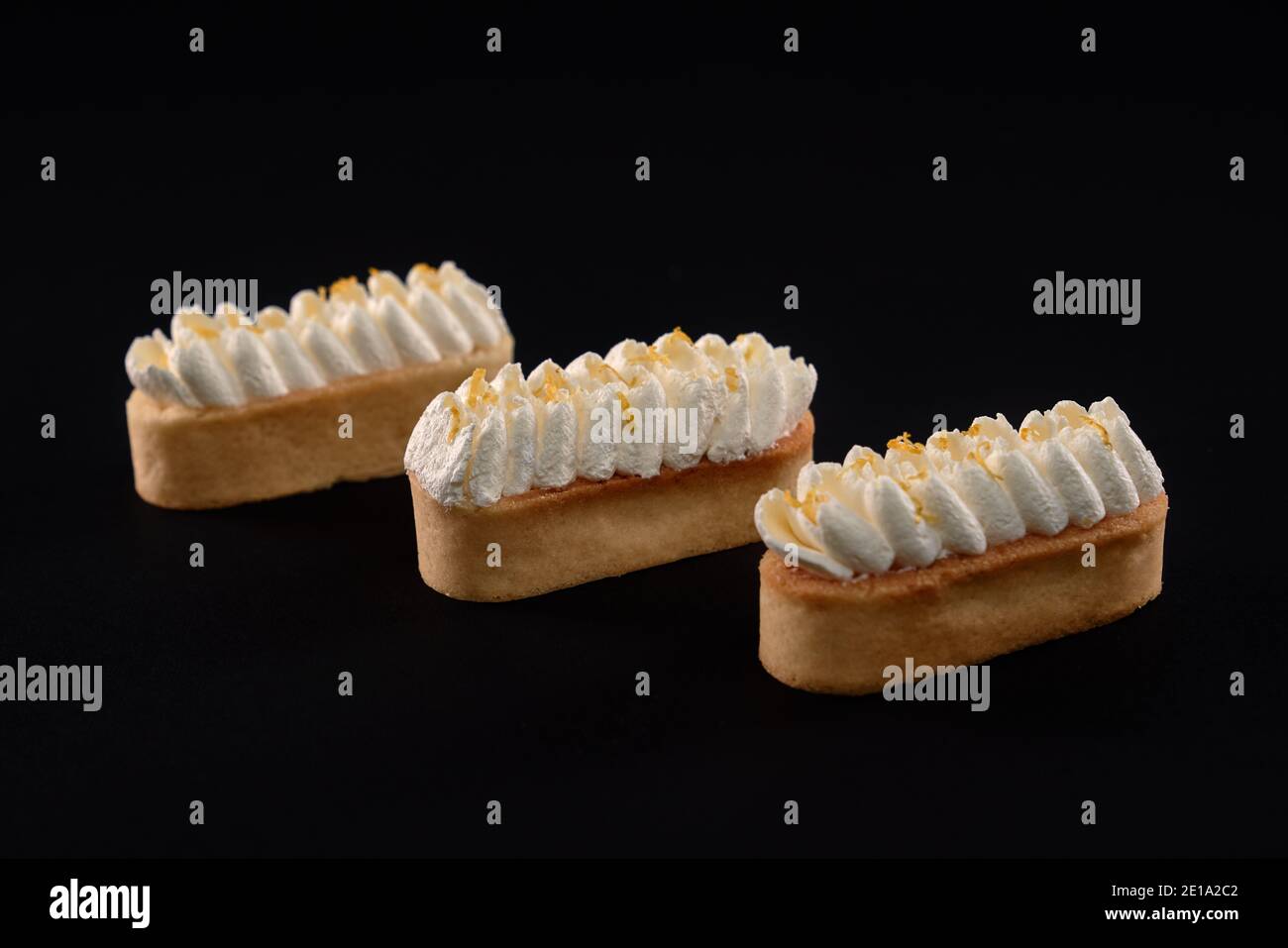 Tre dolci appena fatti in casa, isolati su sfondo nero. Biscotti shortbread con mascarpone panna montata. Concetto di dolci, industria alimentare. Foto Stock