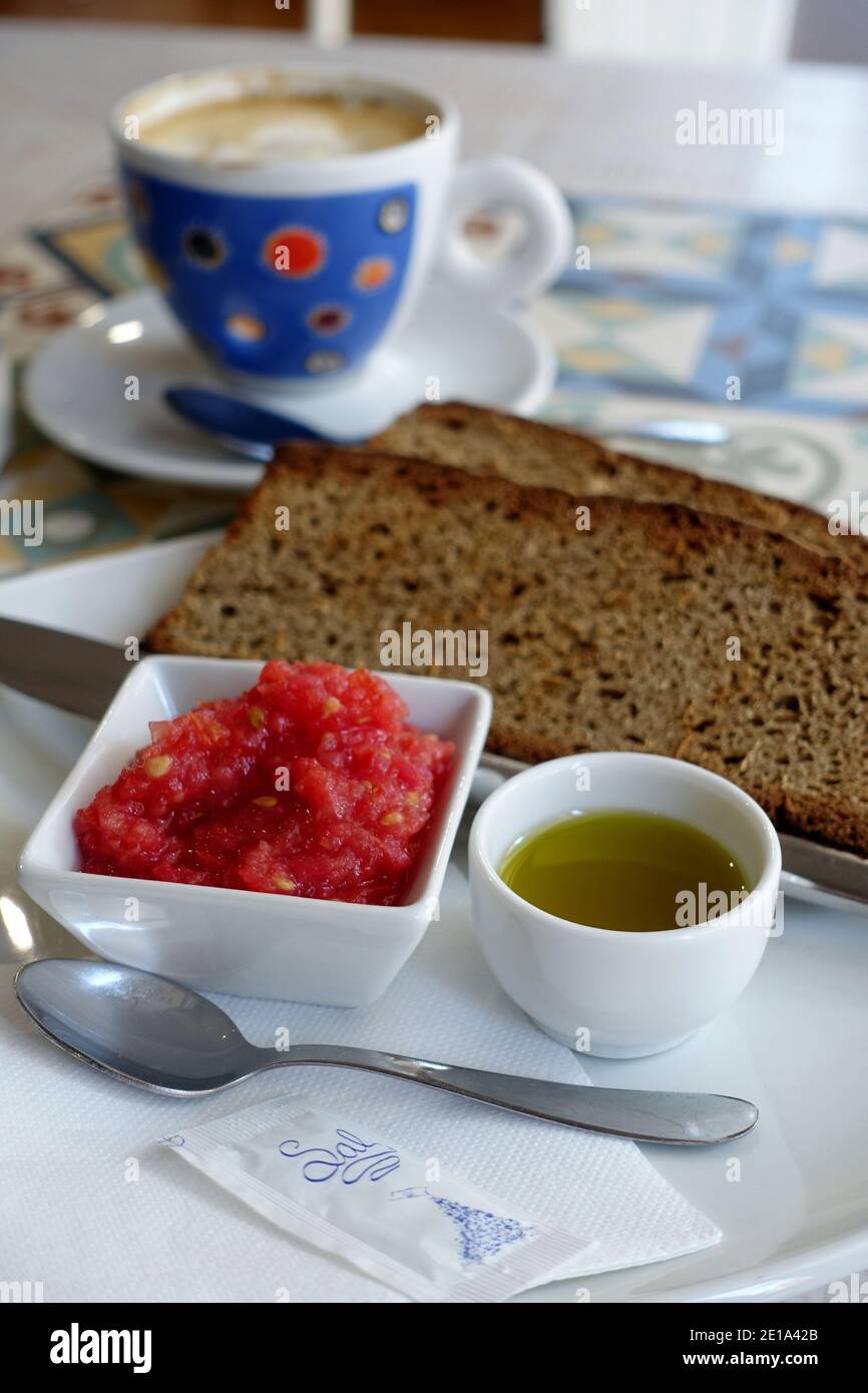 Colazione tradizionale spagnola con pane tostato, pomodoro tritato, olio extravergine di oliva e una tazza di caffè sullo sfondo a Siviglia, Andalusia. Foto Stock
