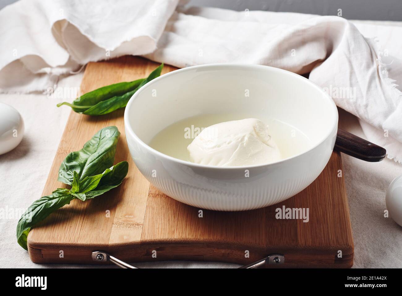 Palla di mozzarella in un recipiente e foglie di basilico fresco. Foto Stock