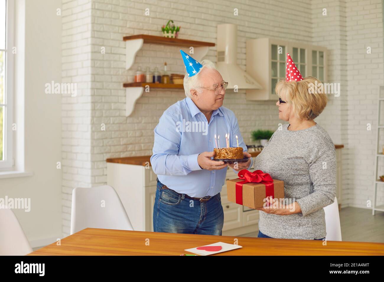 Felice coppia anziana in vacanza cappelli preparazione per festa di compleanno a casa Foto Stock