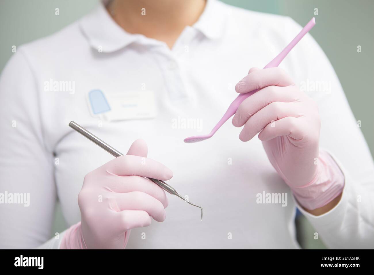 Dentista femminile non riconoscibile che indossa guanti di gomma medica, tenendo in mano gli attrezzi dentali Foto Stock