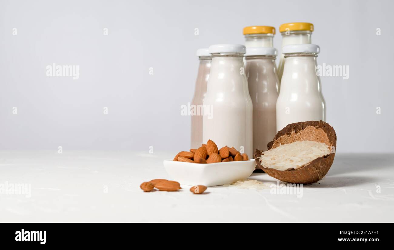 una varietà di latte senza lattosio a partire da noci e grani in bottiglie di vetro. concetto vegano con nocciola, avena, cocco, mandorla, noce Foto Stock