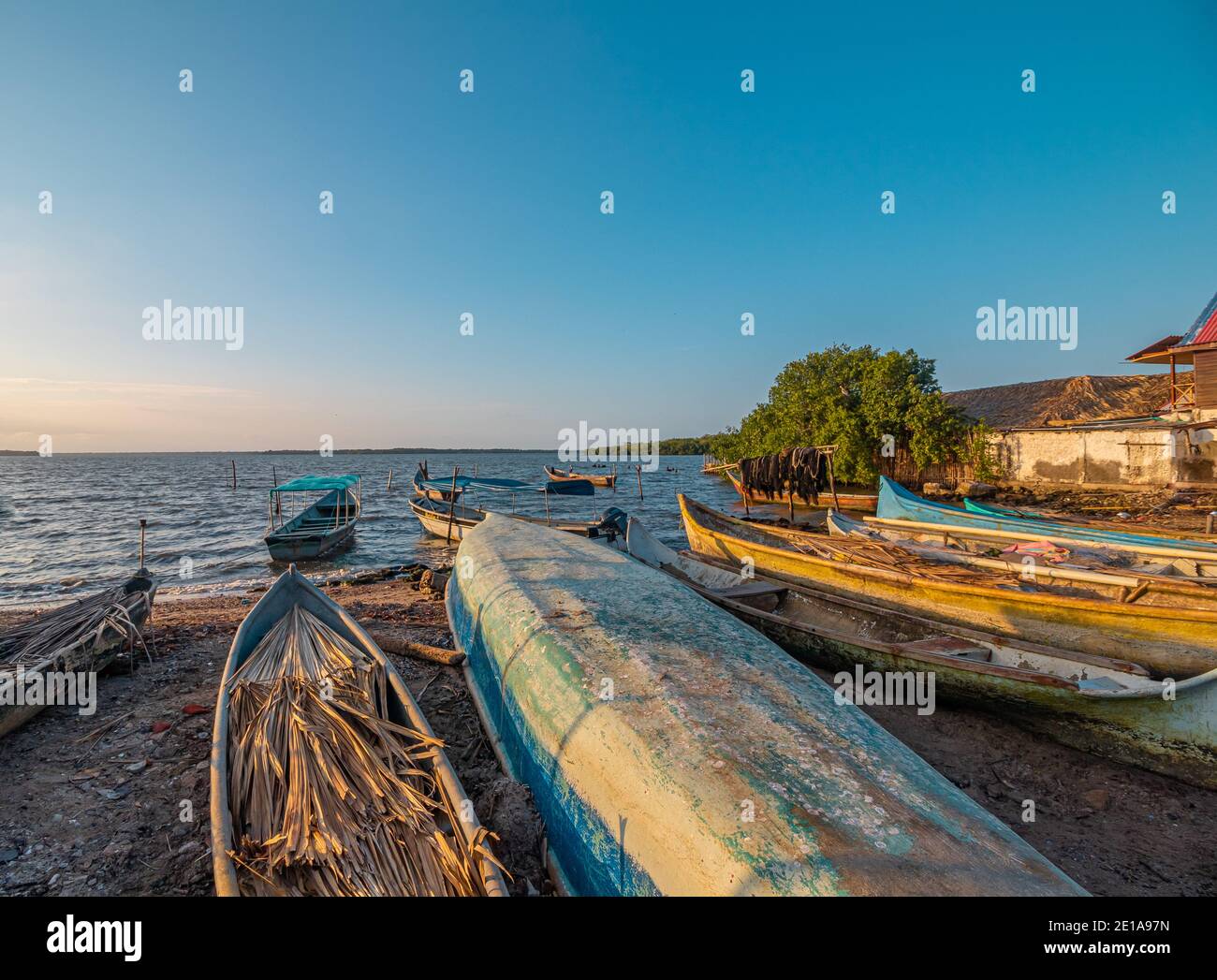 Un gruppo di colorate barche rustiche riposano su a. spiaggia subito dopo le attività di pesca Foto Stock