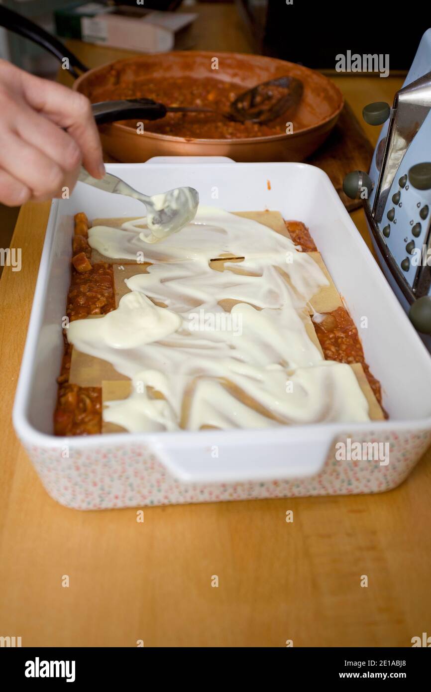 Spalmare la salsa al formaggio Lasagna sulla pasta cruda. Inghilterra Foto Stock